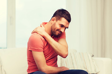 Image showing unhappy man suffering from neck pain at home