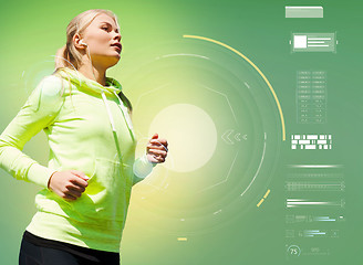 Image showing young woman with earphones running over green