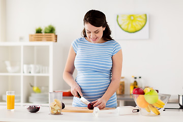 Image showing pregnant woman chopping fruits at home kitchen