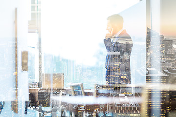 Image showing Businessman talking on a mobile phone while looking through window in NY