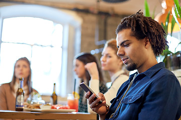 Image showing man with smartphone and friends at restaurant