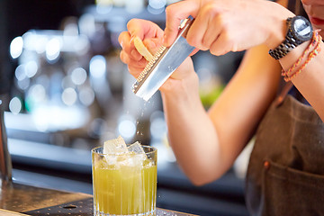 Image showing bartender grates chocolate to cocktail at bar