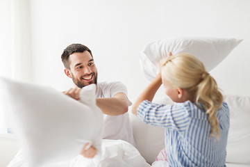 Image showing happy couple having pillow fight in bed at home