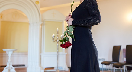 Image showing sad woman with red rose at funeral in church