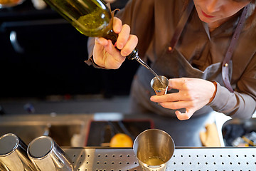 Image showing bartender pouring alcohol into jigger at bar