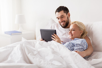 Image showing smiling happy couple with tablet pc in bed at home