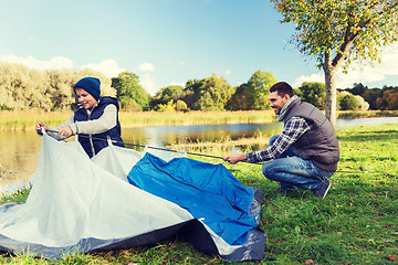 Image showing happy father and son setting up tent outdoors