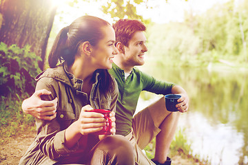 Image showing happy couple with cups drinking in nature