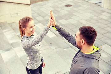 Image showing smiling couple making high five on city street