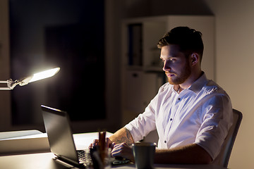 Image showing man with laptop and coffee working at night office