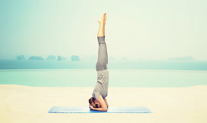 Image showing woman making yoga in headstand pose on mat