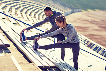 Image showing couple stretching leg on stands of stadium