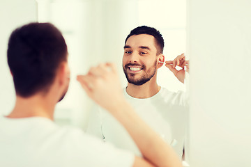 Image showing man cleaning ear with cotton swab at bathroom