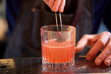 Image showing bartender with glass of cocktail and cherry at bar