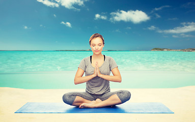 Image showing woman meditating in lotus yoga pose on beach 