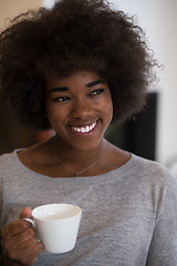 Image showing black woman drinking coffee in front of fireplace