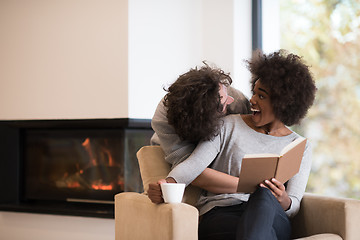 Image showing multiethnic couple hugging in front of fireplace