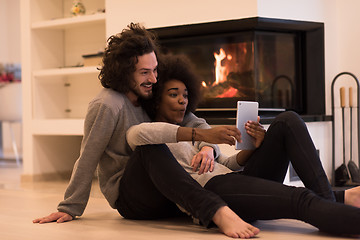 Image showing multiethnic couple using tablet computer on the floor