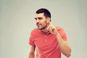 Image showing man having hearing problem listening to something