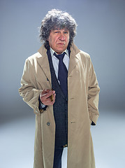 Image showing The senior man with cigar as detective or boss of mafia on gray studio background