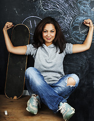 Image showing young cute teenage girl in classroom at blackboard seating on ta