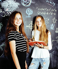 Image showing back to school after summer vacations, two teen real girls in classroom with blackboard painted together, lifestyle people concept