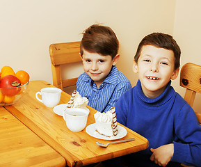 Image showing little cute boys eating dessert on wooden kitchen. home interior