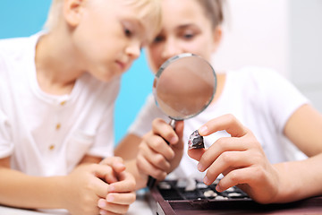 Image showing Casket minerals, a collection of stones. Siblings watching stones under a magnifying glass. Malachite, a child watching a collection of rocks and minerals