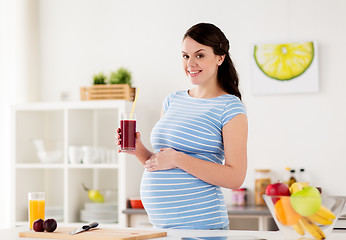 Image showing happy pregnant woman drinking juice at home