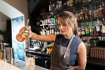 Image showing barmaid with glass and jug preparing cocktail