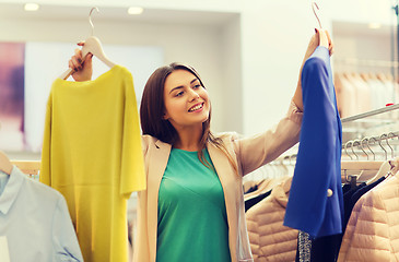 Image showing happy young woman choosing clothes in mall