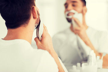 Image showing close up of man removing shaving foam from face