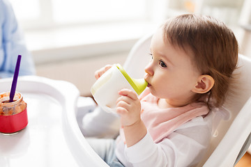 Image showing baby drinking from spout cup in highchair at home