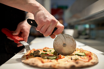 Image showing cook cutting pizza to pieces at pizzeria