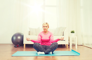 Image showing happy woman stretching leg on mat at home