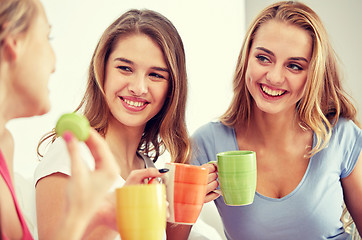 Image showing happy young women drinking tea with sweets at home