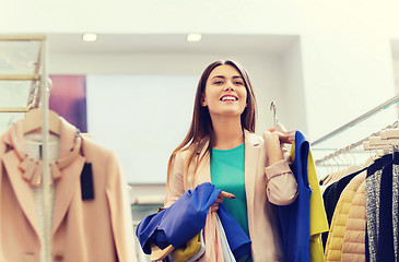 Image showing happy young woman choosing clothes in mall