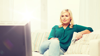 Image showing smiling woman with remote watching tv at home