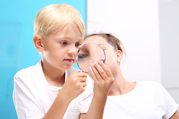 Image showing Steatite, mineral. Geography at school. Mineral. Two children, a girl and a boy watching through a magnifying glass stones from his collection of rocks.