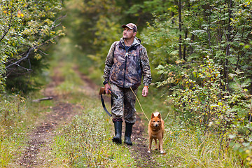 Image showing hunter with dog walking on the road