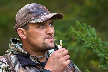 Image showing hunter with a grouse call in the forest