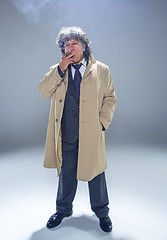 Image showing The senior man with cigar as detective or boss of mafia on gray studio background