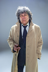 Image showing The senior man with cigar as detective or boss of mafia on gray studio background