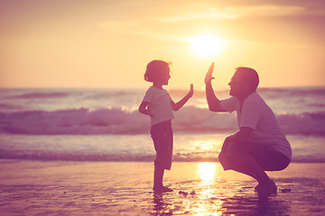 Image showing Father and son playing on the beach at the sunset time.