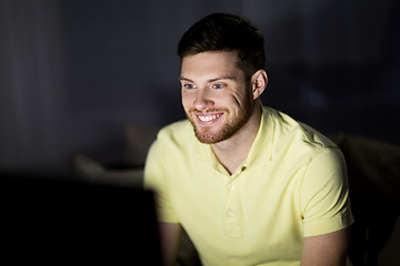 Image showing happy smiling young man watching tv at night