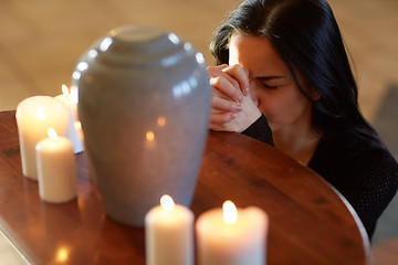 Image showing sad woman with funerary urn praying at church