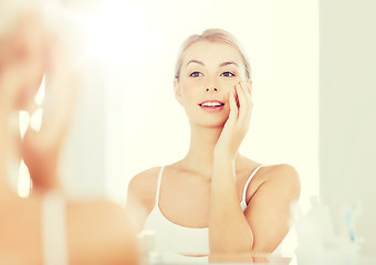 Image showing happy young woman looking to mirror at bathroom