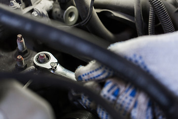 Image showing mechanic man with wrench repairing car at workshop