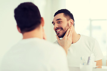 Image showing happy young man looking to mirror at home bathroom