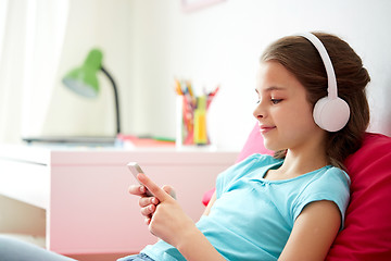 Image showing happy girl with smartphone and headphones at home